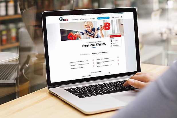 Ein Laptop zeigt die Website der IKK Brandenburg und Berlin mit dem Slogan "Regional. Digital." und einer Suchfunktion.