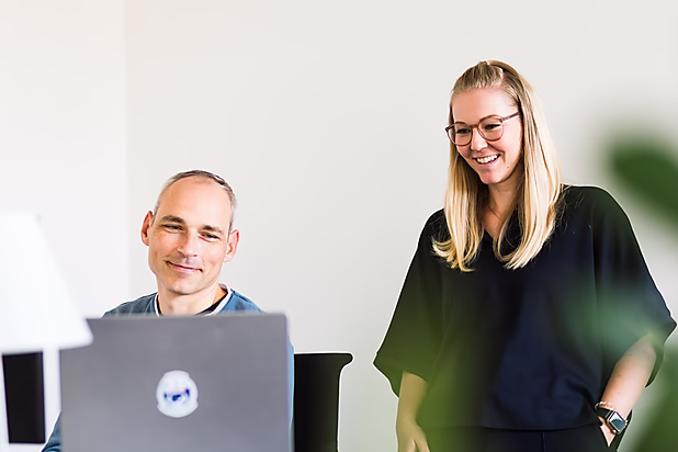 Kollegen lachen während der Arbeit und zeigen die kreative Zusammenarbeit im digitalen Marketing.