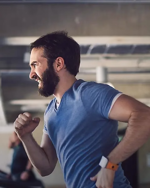 Ein Mann in sportlicher Kleidung joggt auf einem Laufband in einem modernen Fitnessstudio.